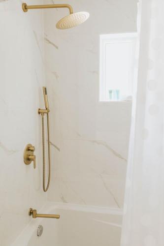 a shower with a gold shower head and a shower curtain at Naramata Courtyard Suites in Naramata
