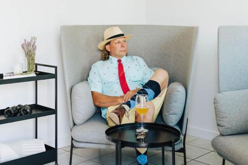 a man in a hat and tie sitting in a chair at Naramata Courtyard Suites in Naramata