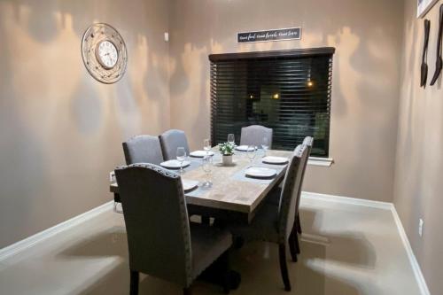 a dining room table with chairs and a clock on the wall at Timeless Memories in Los Fresnos