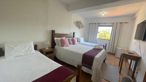 um quarto de hotel com duas camas e uma televisão em Pouso Flor da serra em Tiradentes