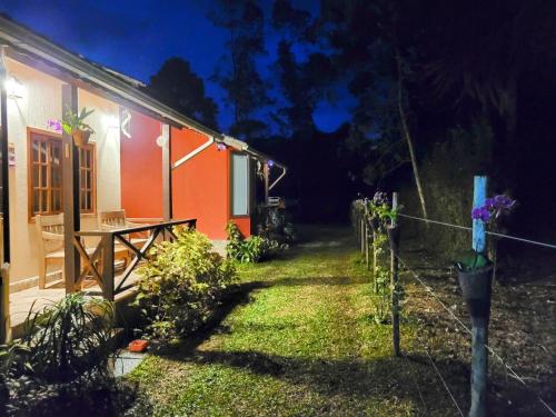 une maison avec une clôture devant elle la nuit dans l'établissement Chalés das Orquídeas, à Visconde de Mauá