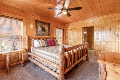 a log cabin bedroom with a bed and a ceiling fan at Soaring High in Pigeon Forge