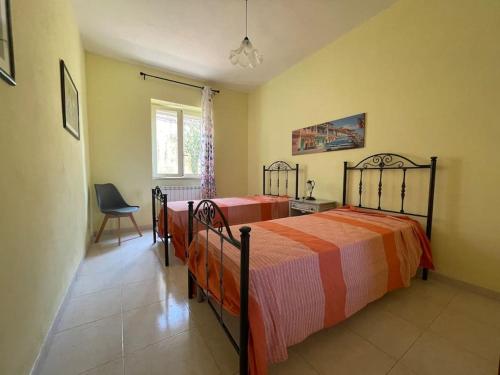 - une chambre avec deux lits, une chaise et une fenêtre dans l'établissement Casa Giulia a Belmonte Calabro, à Belmonte Calabro