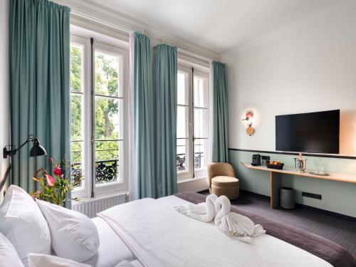 a hotel room with a bed with a tv and windows at Aussen Alster Hotel in Hamburg