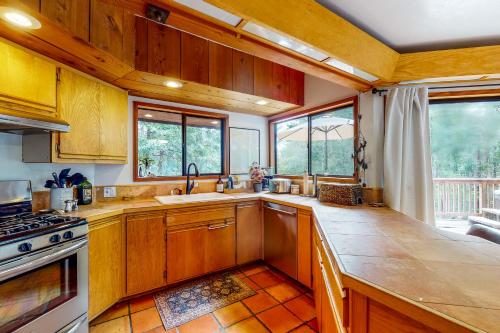 a kitchen with wooden cabinets and a sink and windows at Artist's Retreat in Jenner