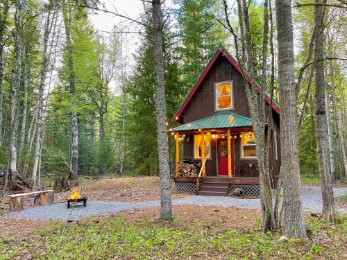 a small cabin in the woods with lights on at Kataluma Inn, Sandpoint, Idaho - Entire Cozy Cabin, Pet Friendly in Sandpoint
