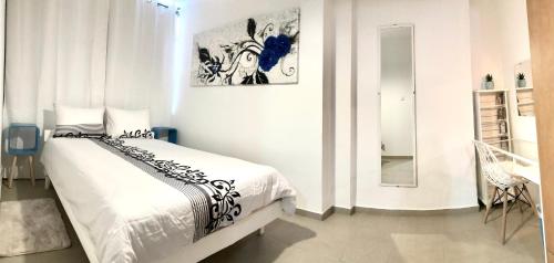 a white bedroom with a bed and a mirror at Stylish Tel Aviv in Tel Aviv