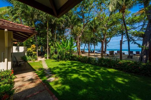 a yard with palm trees and the ocean in the background at The Coast Beachfront Hotel in Tamarindo