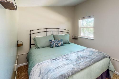 Un dormitorio con una cama con almohadas azules y una ventana en Amani en Onalaska