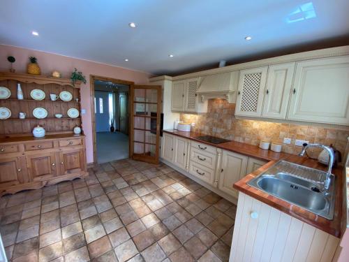 a kitchen with white cabinets and a sink at Bedw Arian Cottage in Benllech