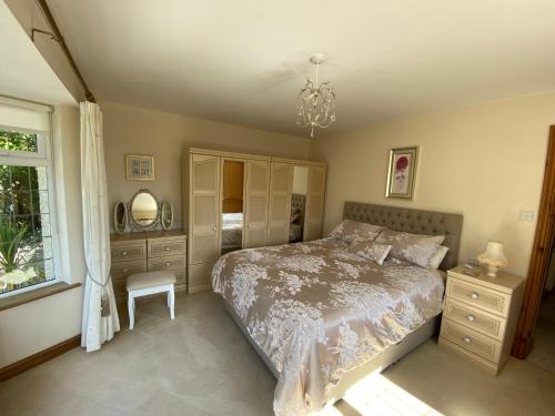 a bedroom with a bed and a window and a chandelier at Bedw Arian Cottage in Benllech