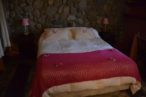 1 dormitorio con 1 cama con manta roja y blanca en Rincon del Valle en San Salvador de Jujuy