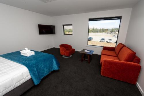 een slaapkamer met een bed en 2 stoelen en een raam bij Tekapo Lakefront Apartments in Lake Tekapo