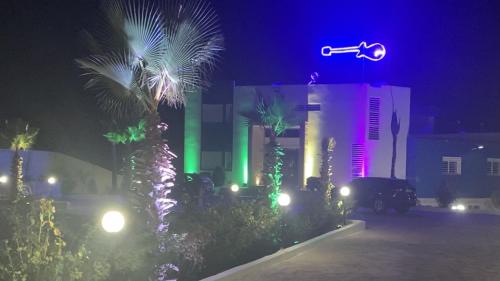 a street light with palm trees and a building at night at GUITAR PALACE - Chambres d'hôtes in Bni Quolla