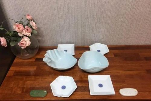 un tavolo con un vaso di fiori e ciotole sopra di SoGoBe Pension a Jeju
