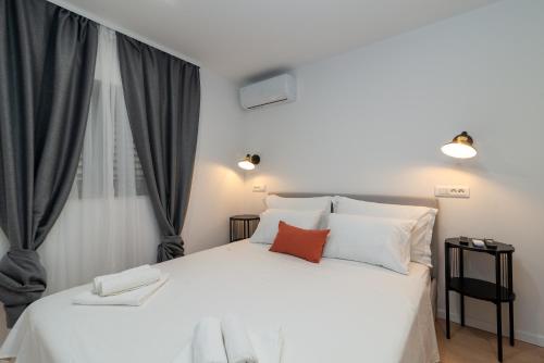 um quarto com uma grande cama branca com almofadas vermelhas em Apartments by the sea Trogir - 21588 em Trogir