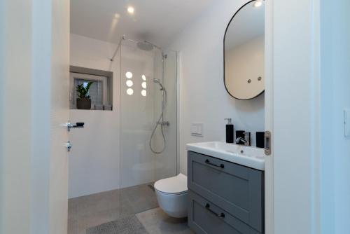 uma casa de banho com um WC, um lavatório e um espelho. em Apartments by the sea Trogir - 21588 em Trogir
