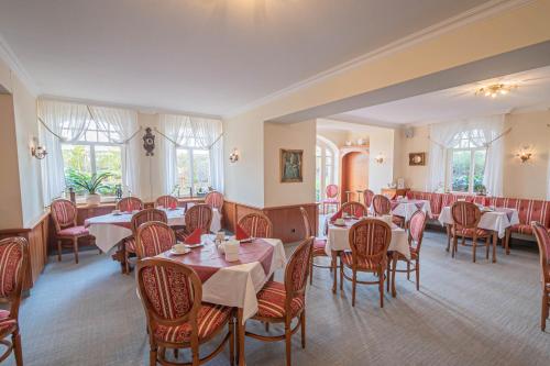 un comedor con mesas, sillas y ventanas en Hotel Imperial Rügen, en Binz