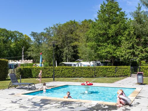 a group of children playing in a swimming pool at Beautiful cottage with dishwasher, in a holiday park not far from Giethoorn in De Bult
