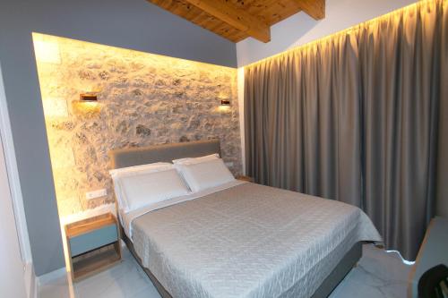 1 dormitorio con cama y pared de piedra en Elais Luxury Villas, en Parga
