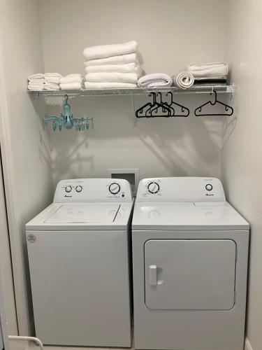 a laundry room with two white washers and a shelf with towels at Appartement Le Yin in Sainte-Anne-de-Beaupré