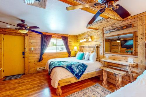 Dormitorio en cabaña de madera con cama y ventilador de techo en Cedaredge Lodge, Cabin 1 en Cedaredge
