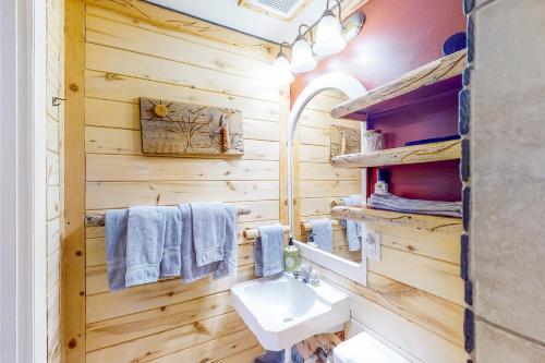 baño con paredes de madera, lavabo y espejo en Cedaredge Lodge Cabin 4 en Cedaredge