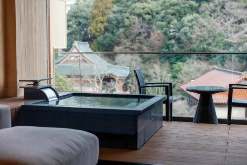 a room with a tub on a balcony with a view at Tachibana Shikitei in Kaga