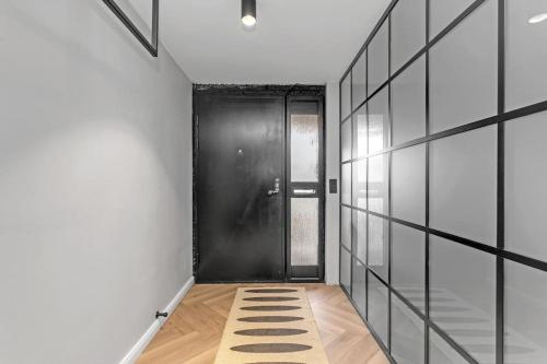 a hallway with a black door and a rug at A modern and stylish furnished house in Reykjavík in Reykjavík
