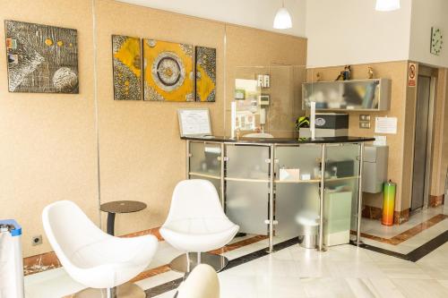 a room with two white chairs and a counter at Hotel Montedobra in Torrelavega
