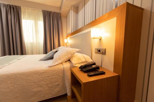 a bedroom with a bed and a night stand with a telephone at Hotel Montedobra in Torrelavega