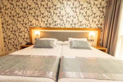 a bedroom with two beds and a wall with triangles at Hotel Montedobra in Torrelavega