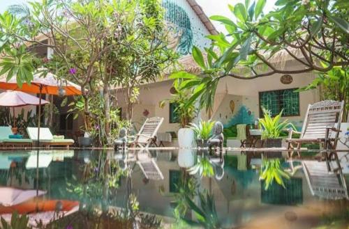 a house with a swimming pool with chairs and umbrellas at Green BOUTiQUE in Siem Reap