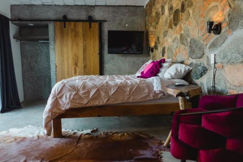 Cama en habitación con pared de piedra en Casa Fenix, en Sayulita