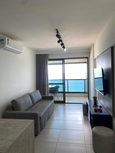 ein Wohnzimmer mit einer Couch und einem Tisch und einem Fernseher in der Unterkunft Barra 535 Vista Mar in Salvador