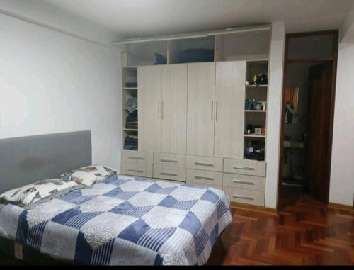 a bedroom with a blue and white bed and white cabinets at Departamento céntrico in Huaraz