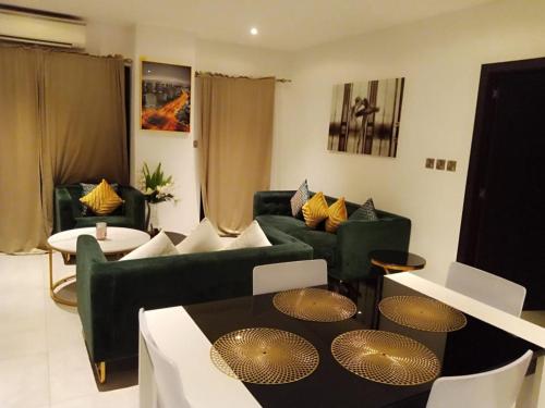 ein Wohnzimmer mit einem grünen Sofa und einem Tisch in der Unterkunft KMAX PROPERTY in Accra