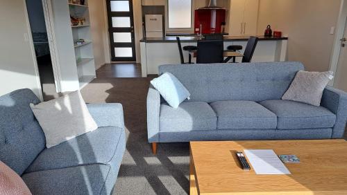 Sala de estar con 2 sofás azules y mesa de centro en South City Accommodation unit 4 en Invercargill