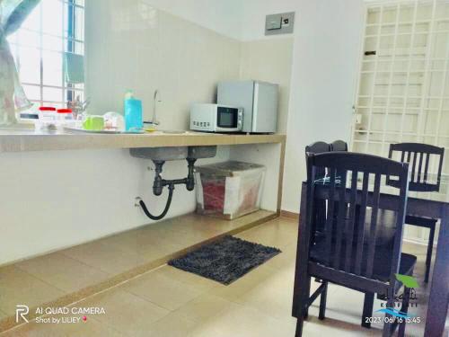 een keuken met een aanrecht met een magnetron en een stoel bij Qalya Homestay 1 @ Kota Bharu in Kota Bharu
