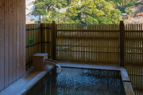 a pool in a fence with a water fountain at Tachibana Shikitei in Kaga