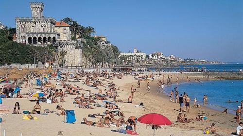 a crowd of people on a beach with the ocean at Villa Pietra Estoril Eco Guesthouse in Estoril