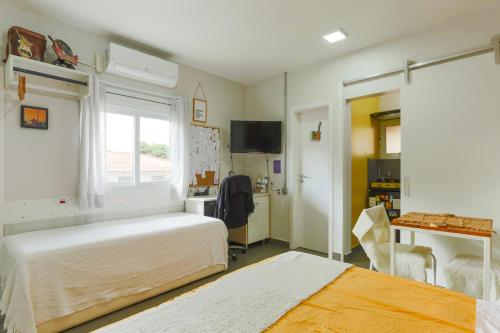 a bedroom with two beds and a window and a desk at La Casita Bem Gaúcha in Porto Alegre