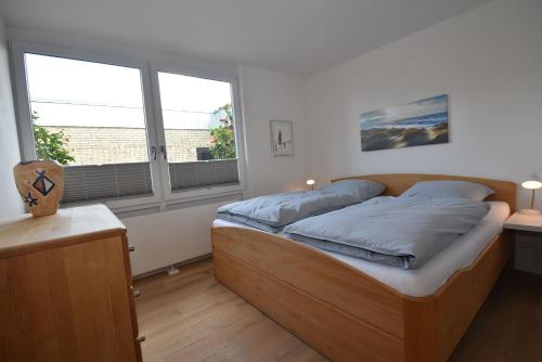 Bett in einem Zimmer mit einem großen Fenster in der Unterkunft fewo1846 - Nordlicht - zentral gelegene Wohnung im EG mit Wintergarten und Terrasse in Harrislee