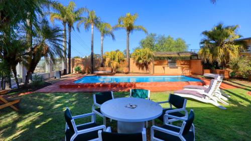 a backyard with a table and chairs and a pool at Hilltop Motel in Broken Hill