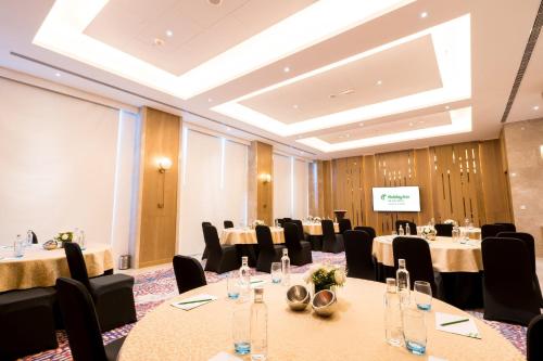 a conference room with tables and chairs and a screen at Holiday Inn Lucknow Airport by IHG in Lucknow