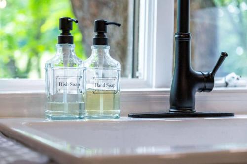 two bottles of alcohol sitting on a sink next to a faucet at Unique Stay! Ricketts Chic Farmhouse Retreat with Stargazing Bubble Tent 