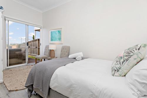 a white bedroom with a bed and a window at Collaroy Beachfront Hideaway - Parking and views in Collaroy