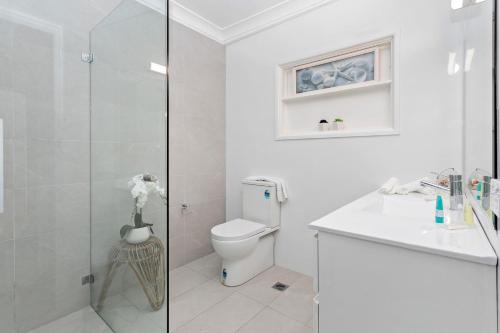 a white bathroom with a toilet and a shower at Collaroy Beachfront Hideaway - Parking and views in Collaroy