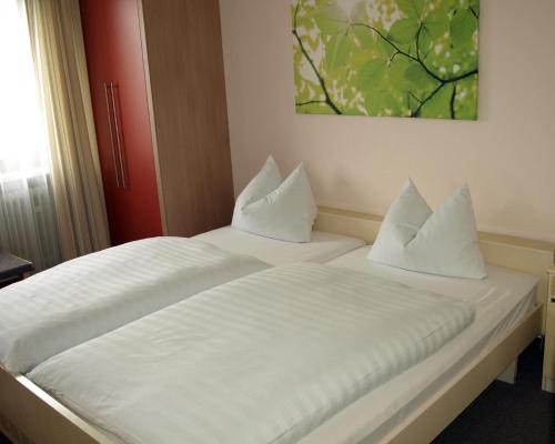 a white bed with two pillows on top of it at Gasthof zur Sonne in Jettingen-Scheppach