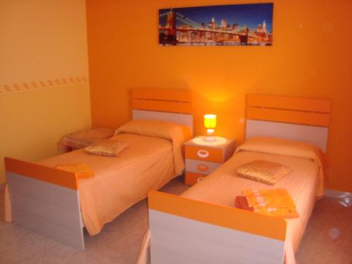 two beds in a room with orange walls at B&B Le Tre rose dell'Etna in Zafferana Etnea